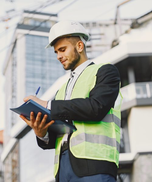 Man in builder uniform holding older. Looking at building plan. Modern city setting.